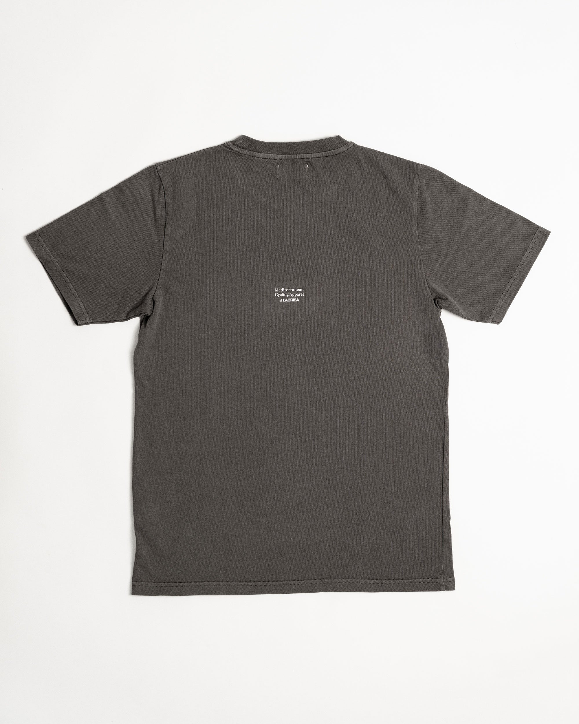 Imagen de la parte trasera de la camiseta de manga corta gris. Se ve el tagline Mediterranean Cycling Apparel en crema que va colocado en pequeño en el centro de la parte de atrás de la camiseta.