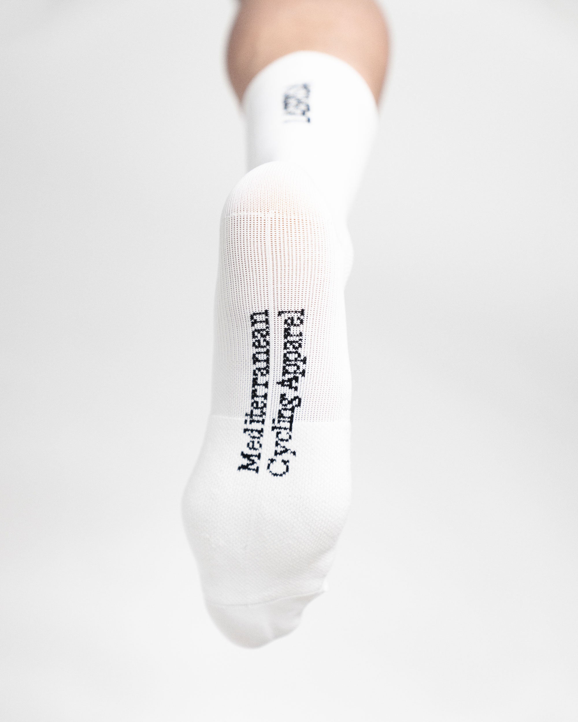 Imagen de la planta de calcetines de ciclismo blancos en la que se lee en negro Mediterranean Cycling Apparel