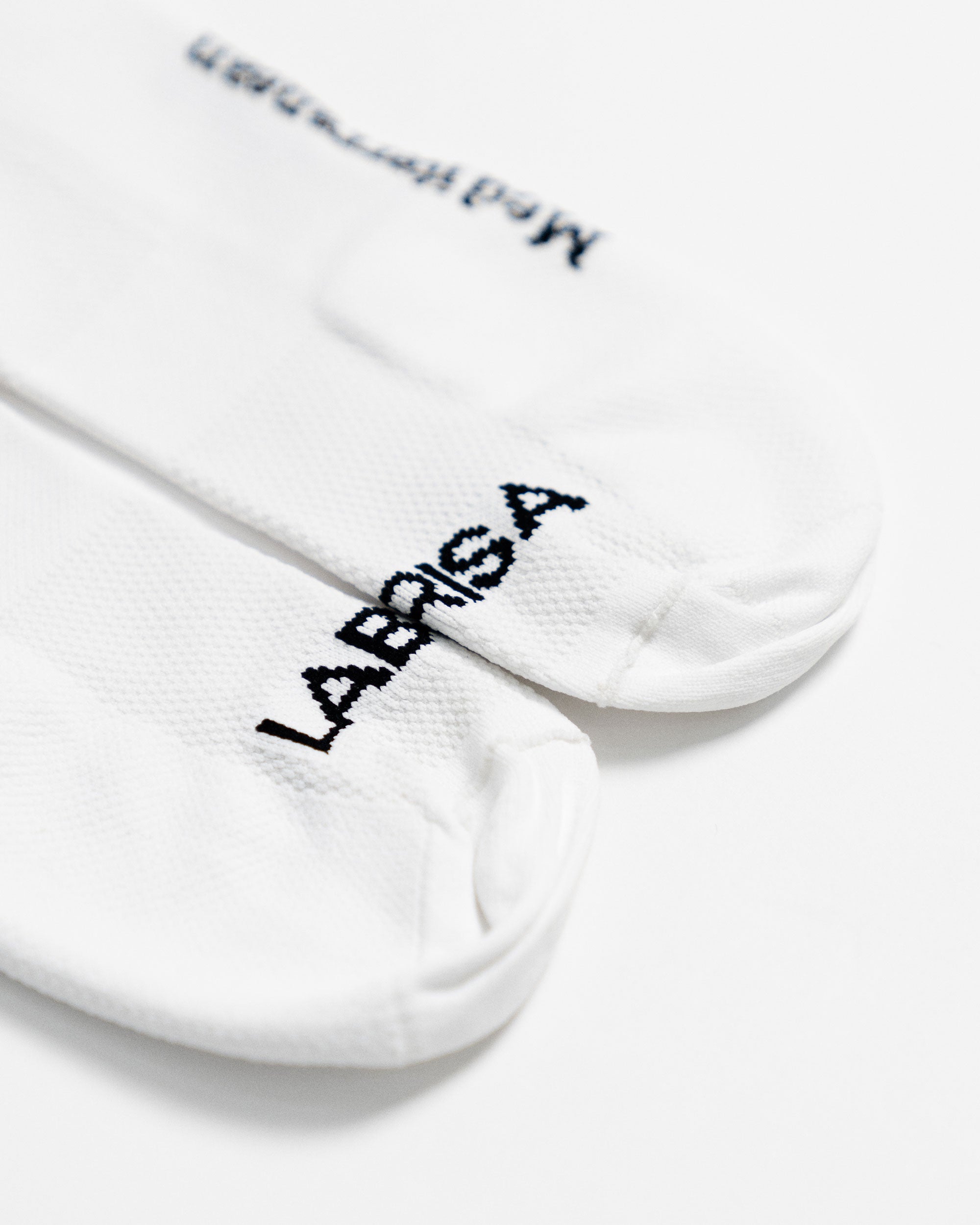 Imagen de detalle de la puntera de calcetines de ciclismo blancos en la que se lee en negro LABRISA