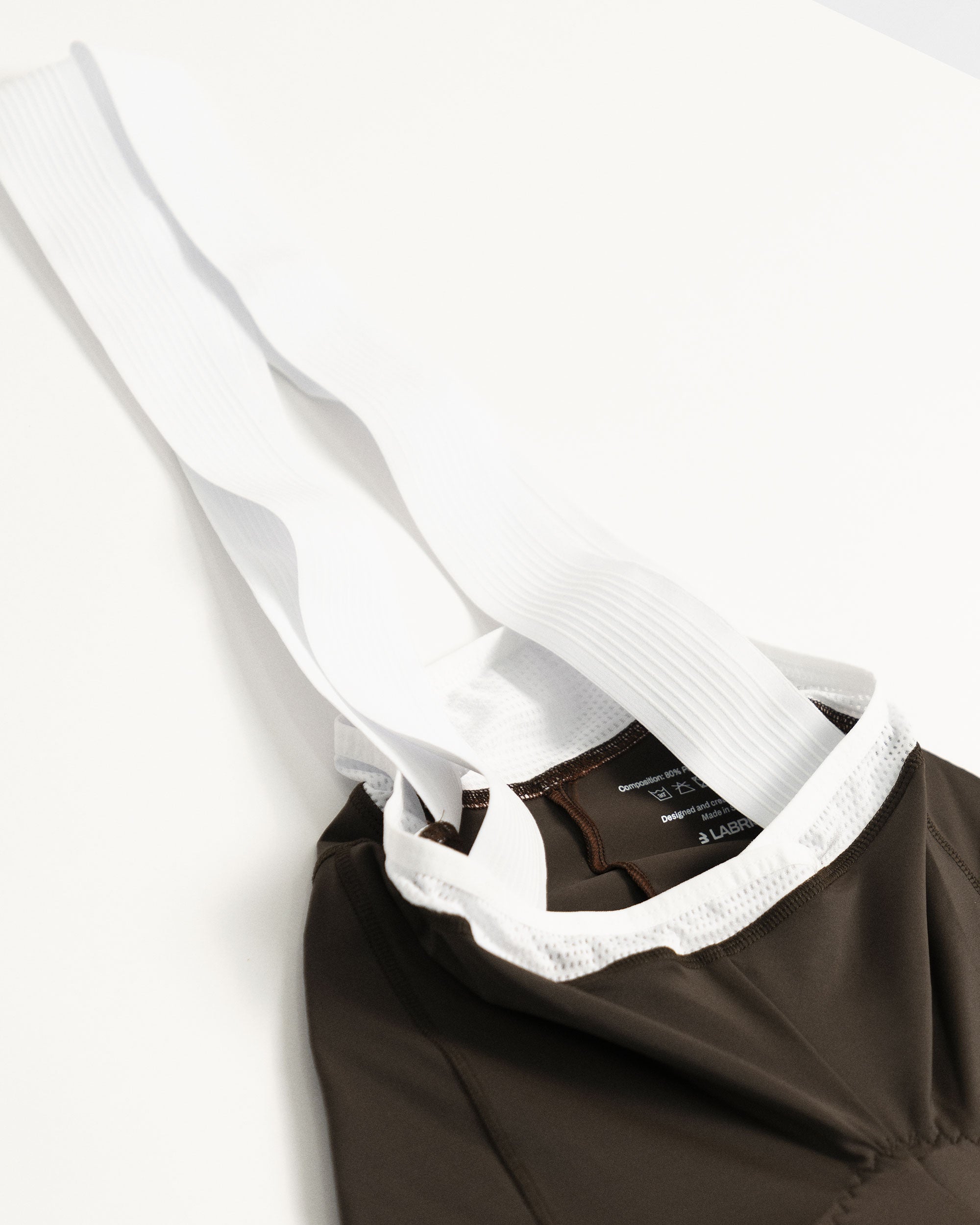 Imagen de culotte de ciclismo de chica marrón. Se ve el detalle de los tirantes que son blancos y rayados, elásticos y cómodos.