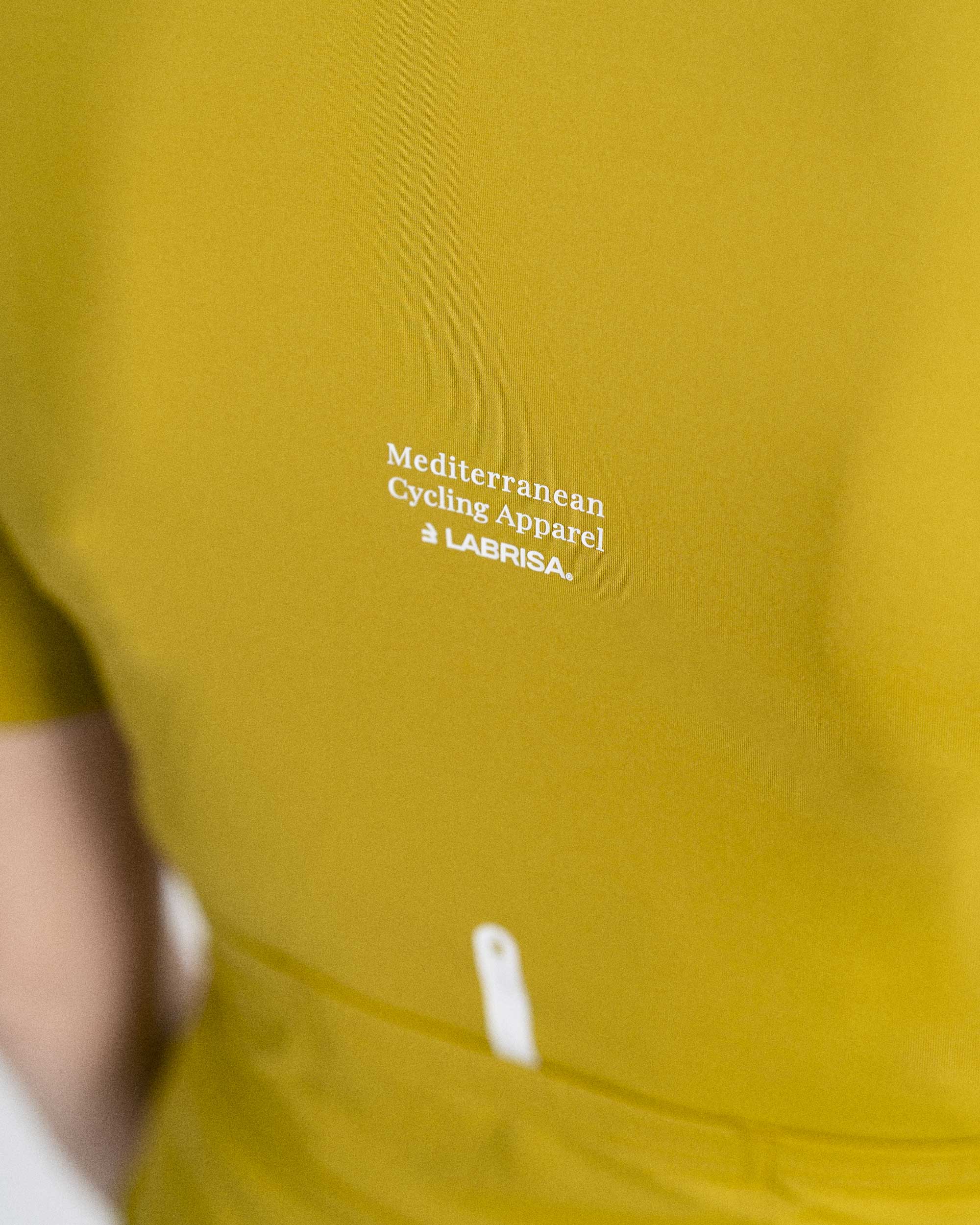 Imagen de detalle de maillot de ciclismo de mujer verde oliva de la parte trasera. Se puede ver el detalle de Mediterranean Cycling Apparel en el centro de la espalda.