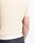 Imagen de detalle de maillot de ciclismo de hombre crema de la parte trasera. Se puede ver una línea reflectante en blanco que sale del bolsillo trasero. 3 bolsillos de alta capacidad en la zona lumbar.