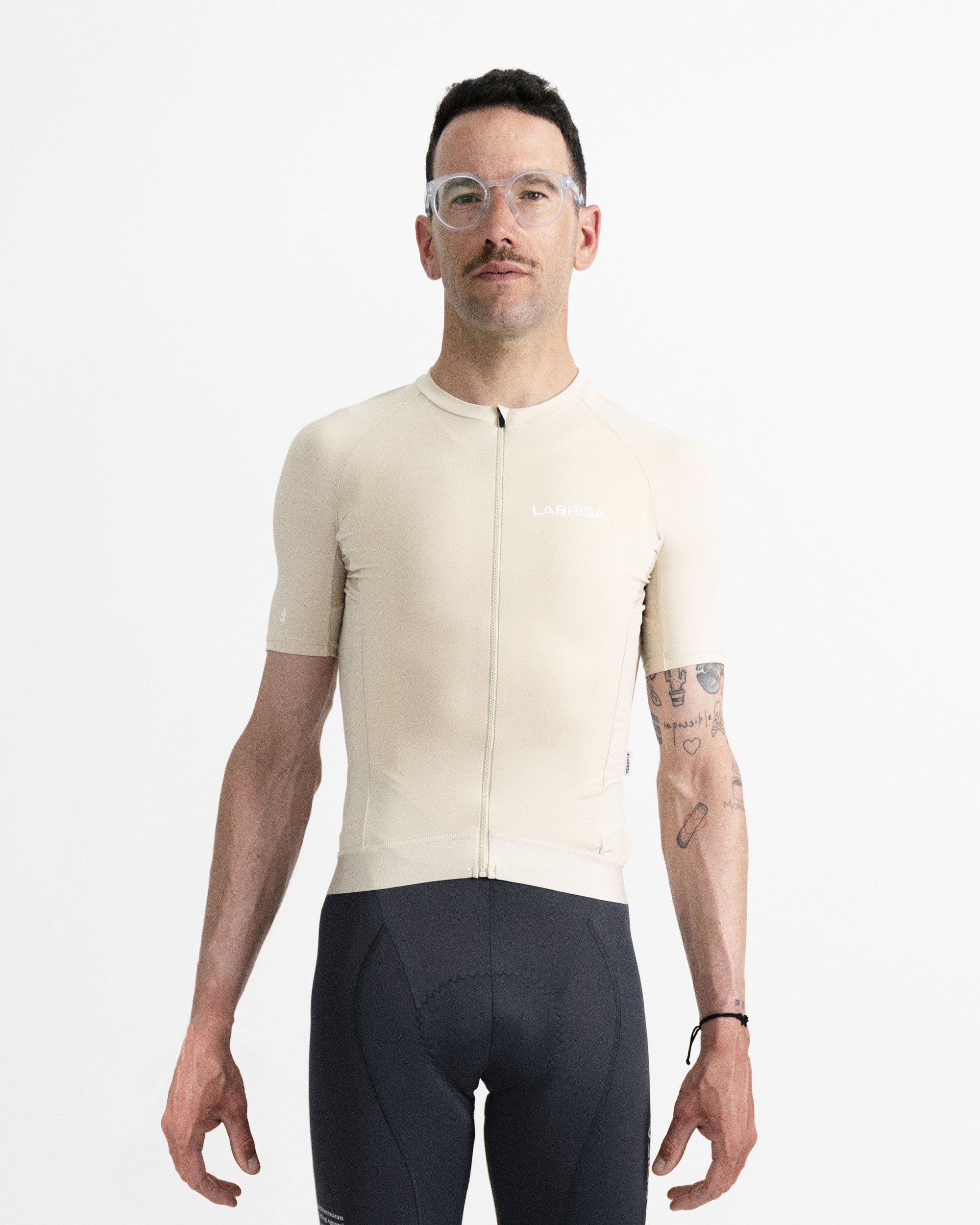Imagen de maillot de ciclismo de hombre  crema en modelo visto de frente. Logotipo de LABRISA en blanco en el pecho izquierdo e isotipo en blanco de la B en el bíceps derecho. Cremallera, siliconas y demás detalles al mismo tono crema. 