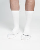 Imagen de delantera de calcetines  de ciclismo blancos en la que se lee en la puntera en negro LABRISA 