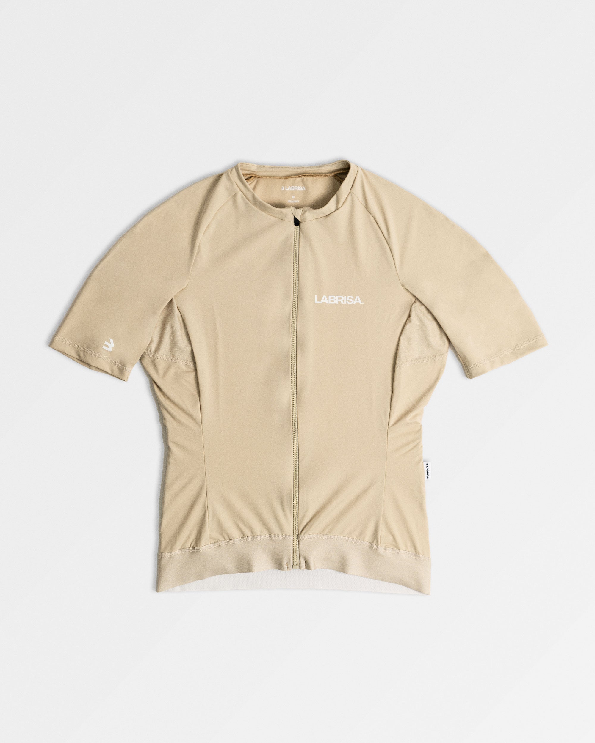 Imagen de maillot de ciclismo de mujer crema. Logotipos en blanco de LABRISA en el pecho izquierda y la B en el bíceps derecho. La cremallera y siliconas al mismo tono crema.