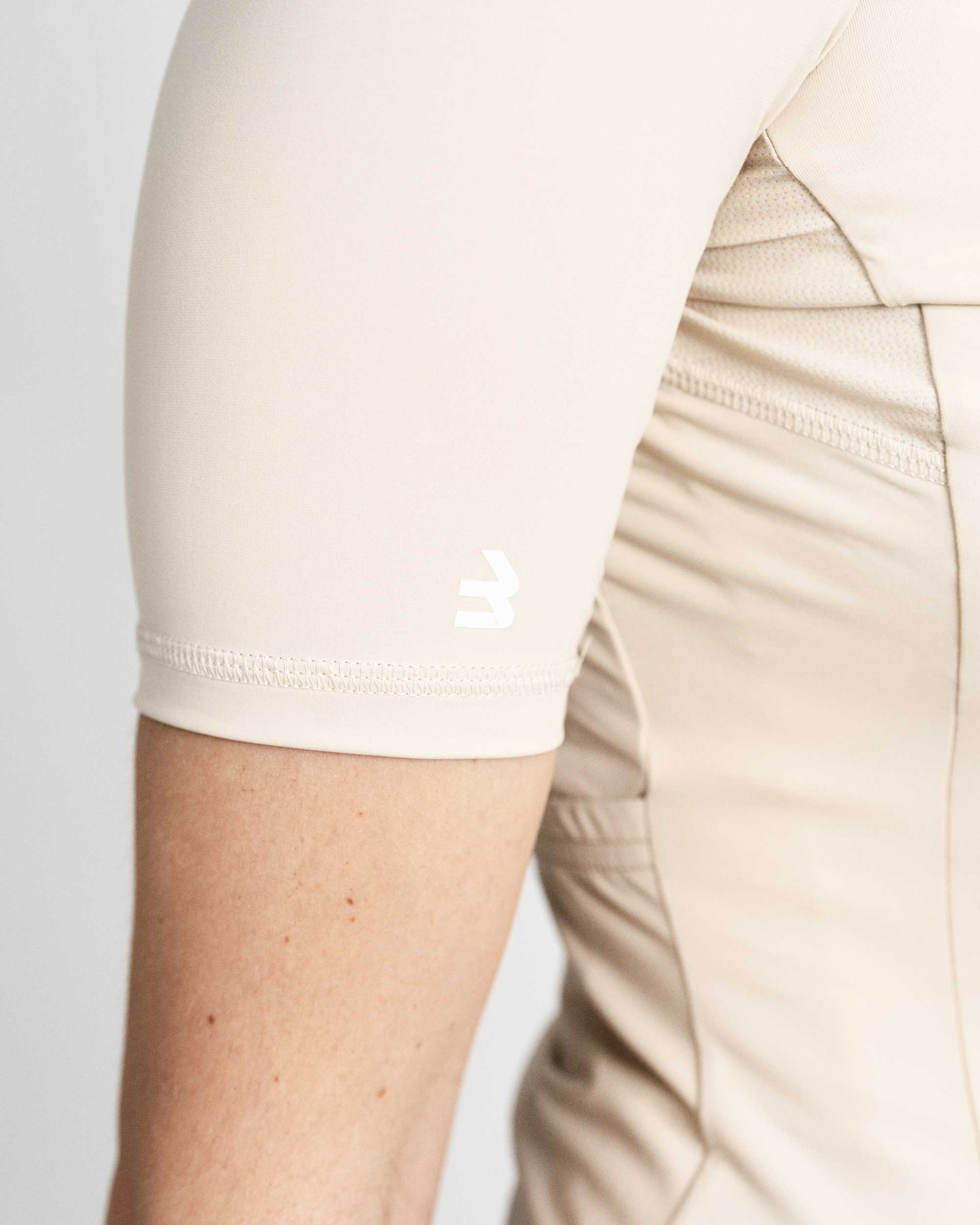 Imagen de detalle de maillot de ciclismo de mujer crema de la manga. Se puede ver el logotipo de LABRISA en forma de B en blanco en el bíceps. 