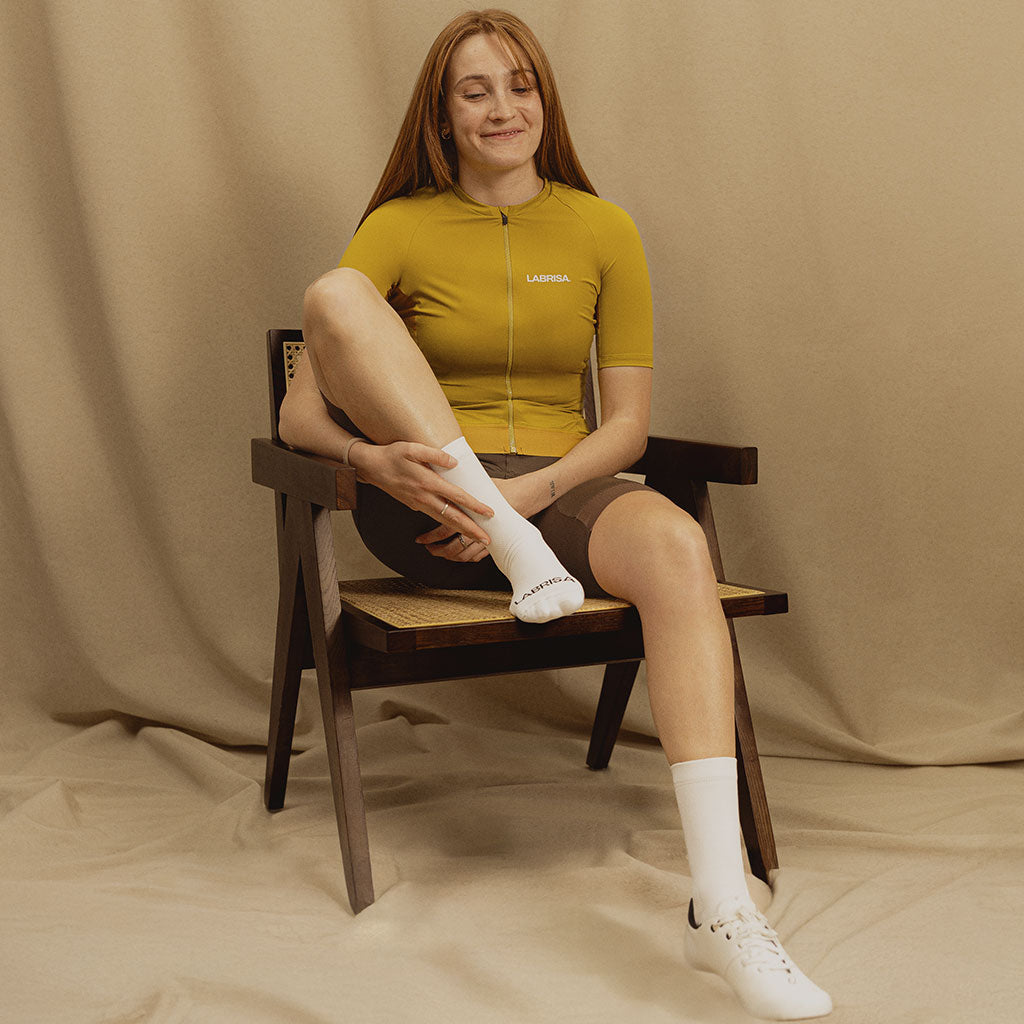 Imagen de mujer vestida de ciclismo sentada en una silla con una pose relajada y sonriendo